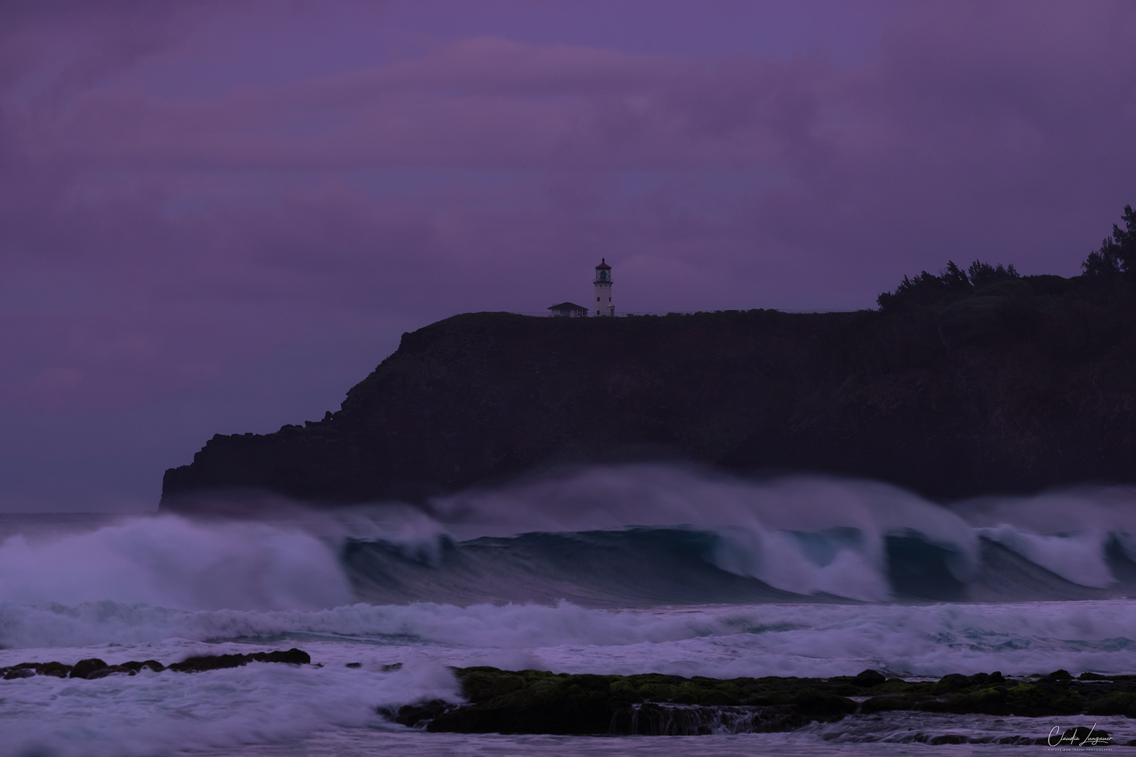 Big waves at Secret Beach, Kauai in Hawaii with Kilaulea lighthouse in the background.
