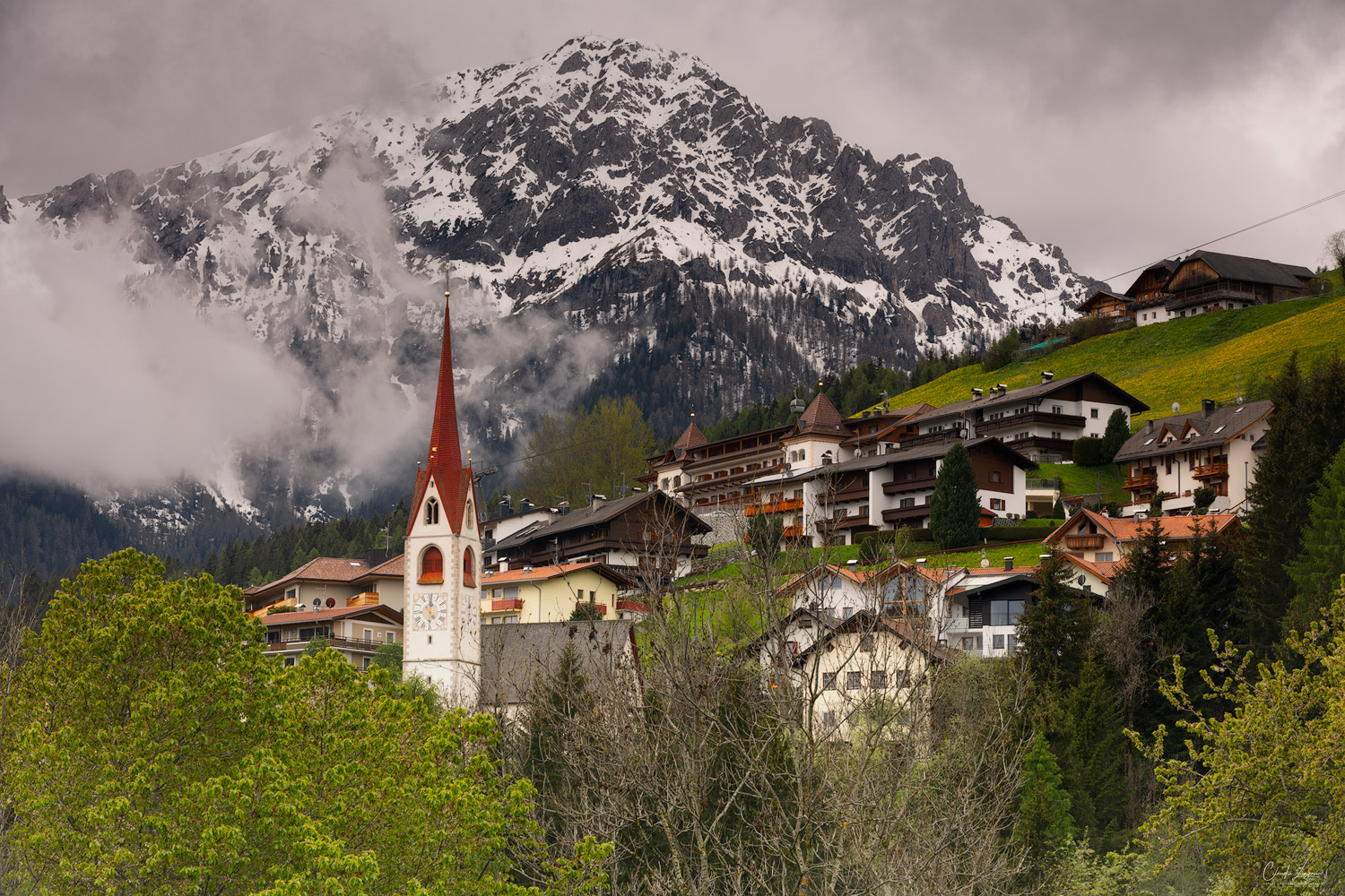 View on a small village and snow covered Mountain Peak in the Dolomites.