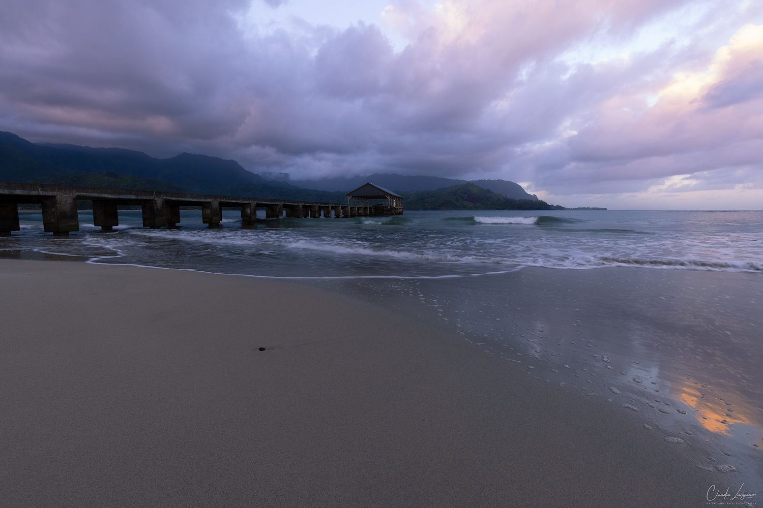 Dramatic clouds forming over Hanalei Pier and the rolling mountains on Kauai island in Hawaii.